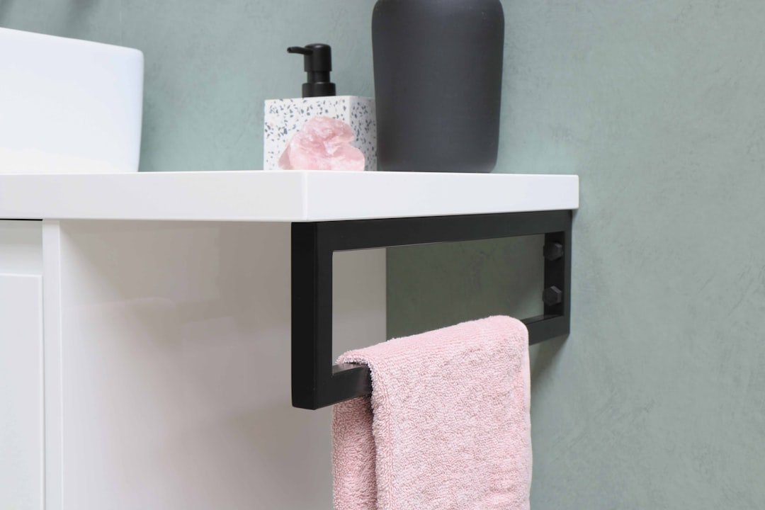 A pink hand towel hanging from a rail built into a bathroom vanity.