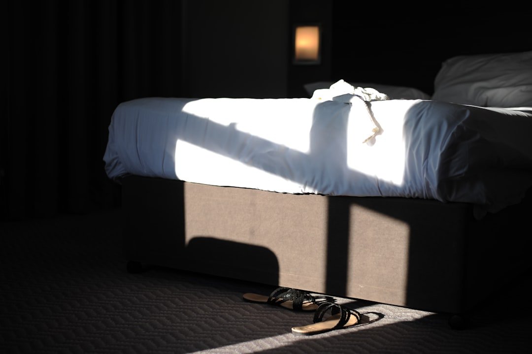 A low bed with shoes and accessible storage space underneath.