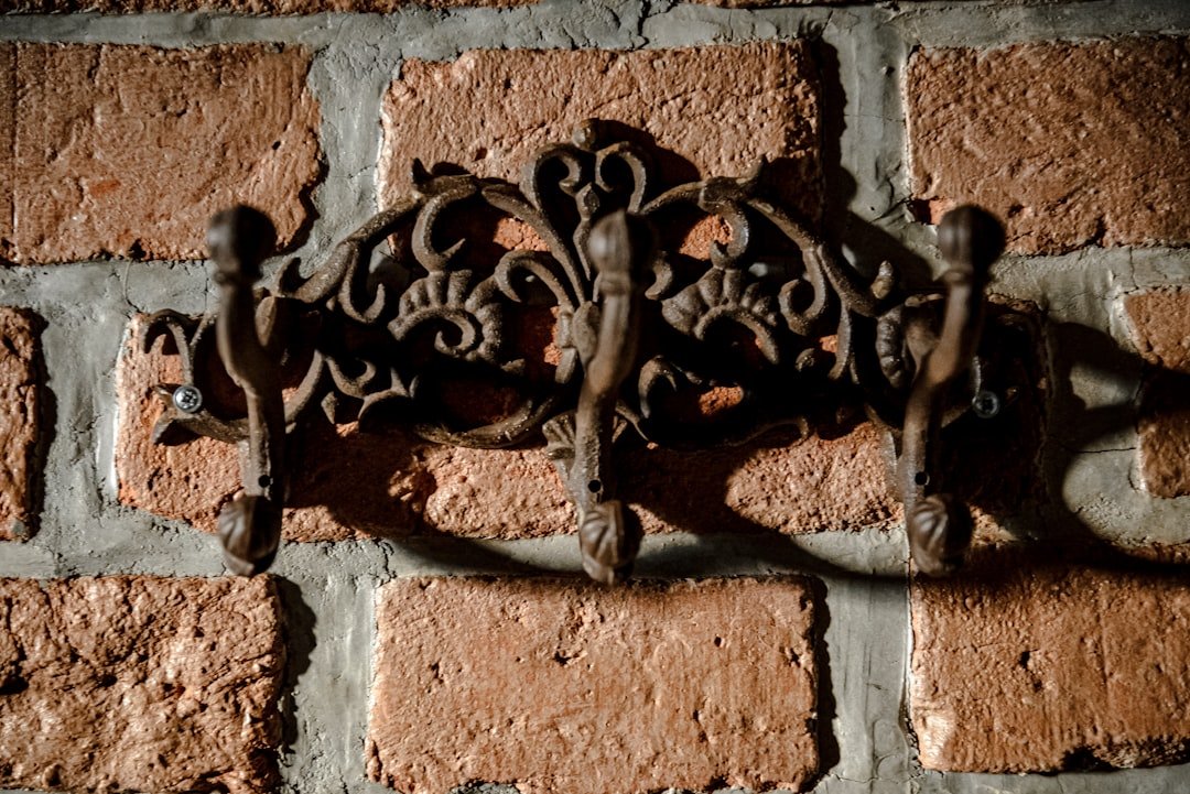 Ornate metal coat rack on brick wall
